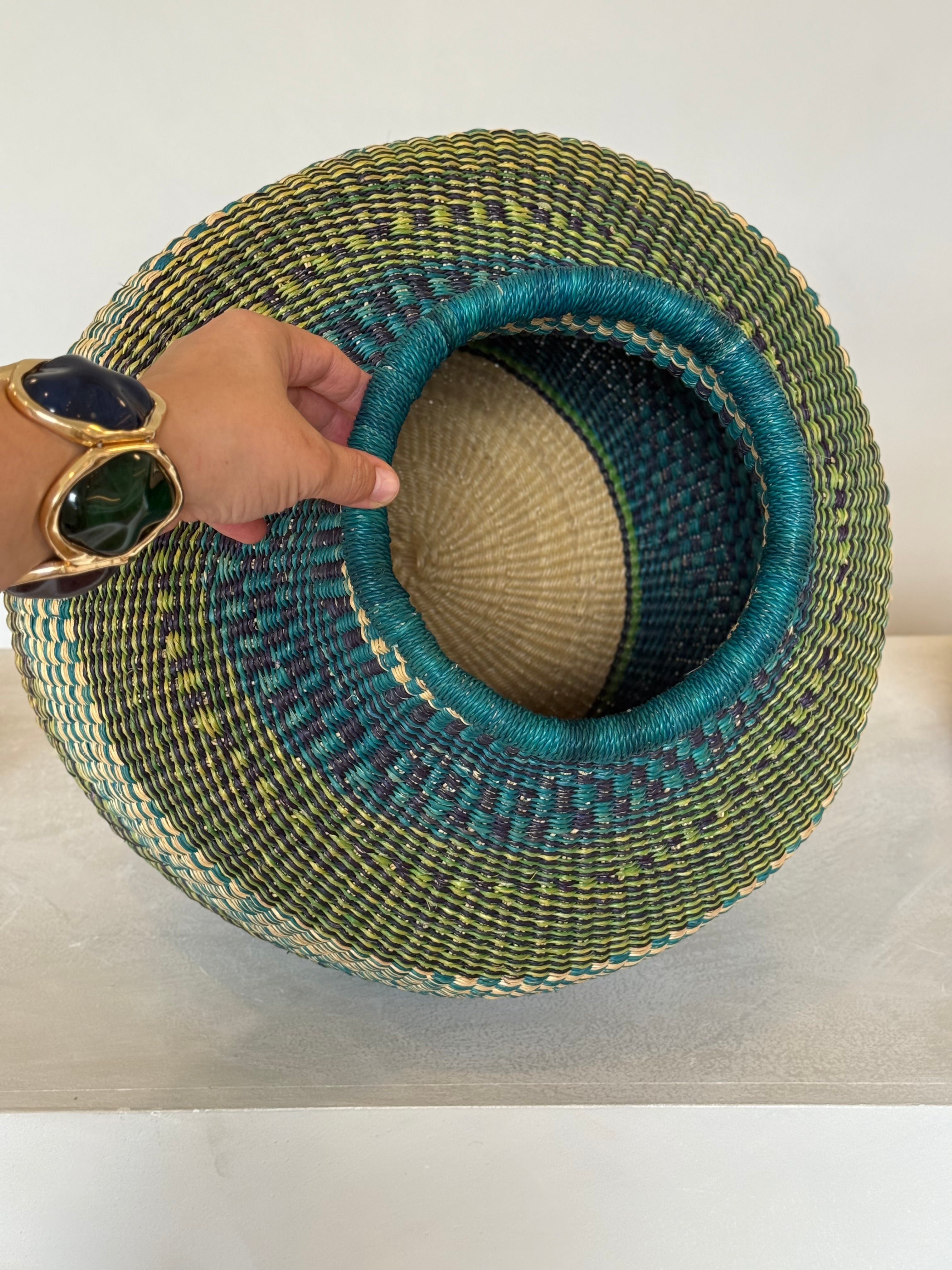 Top view of teal and green handwoven basket, showing wide opening and intricate interior weave.